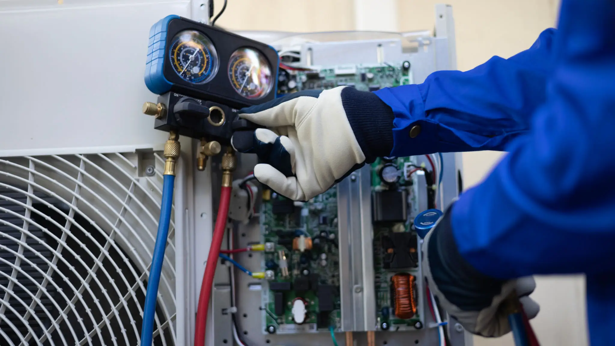 Technician adjusting HVAC system gauges with gloved hand.