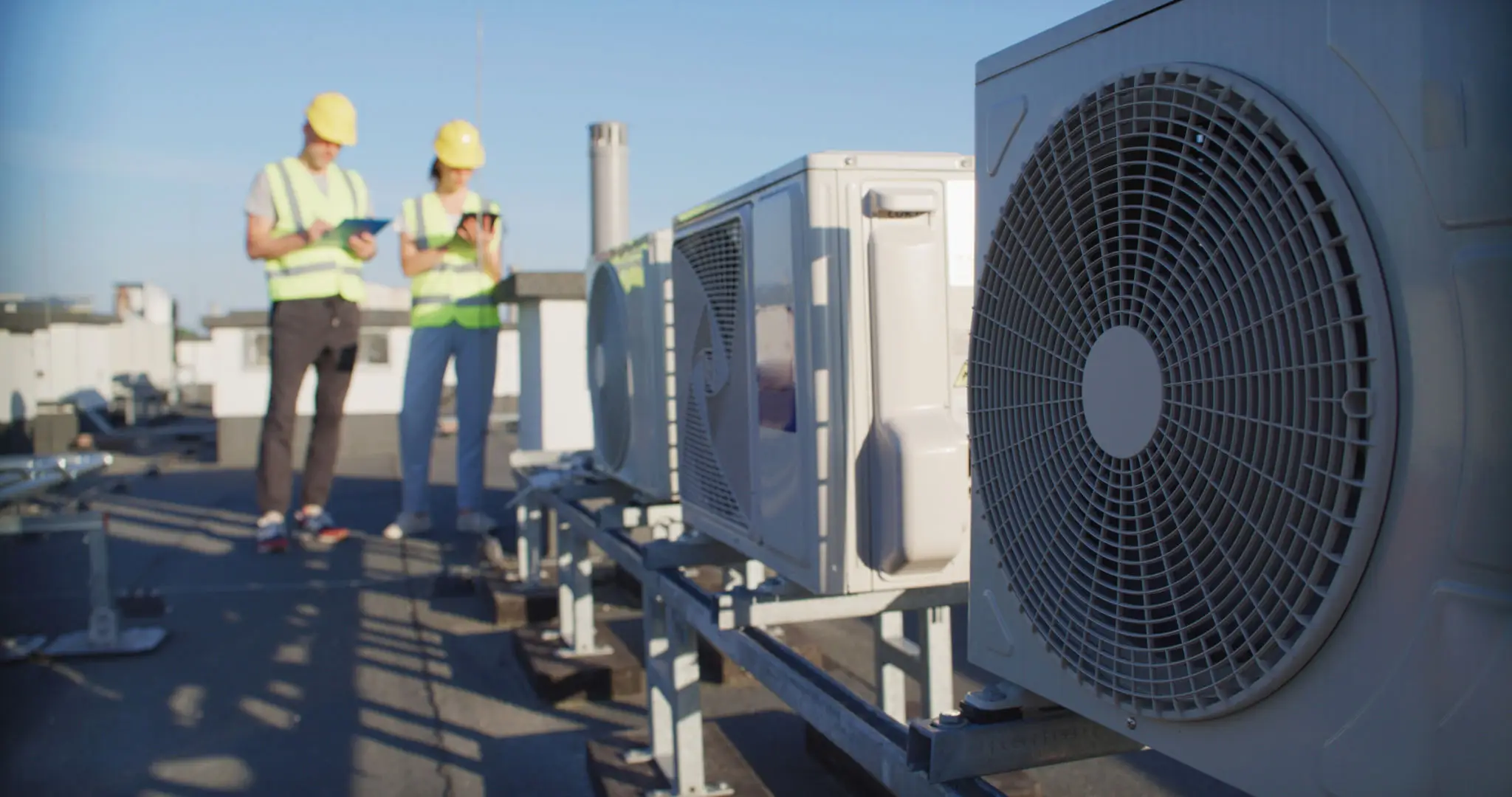 Technician inspecting rooftop HVAC units on a sunny day.