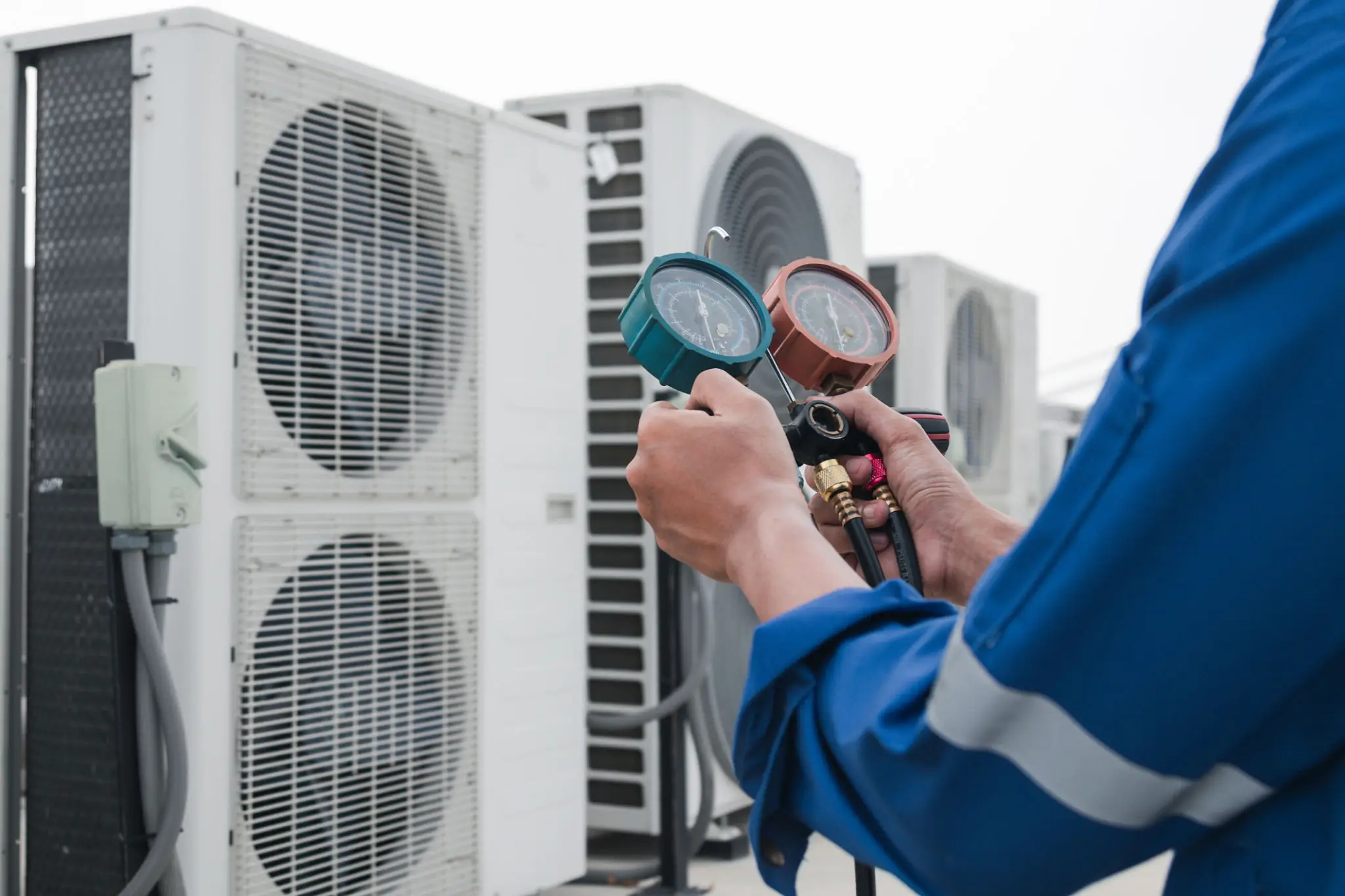 Technician checking air conditioner pressure with gauges.