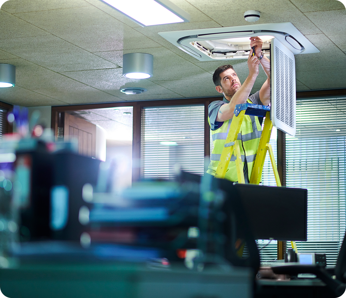 Worker on ladder fixing air vent.