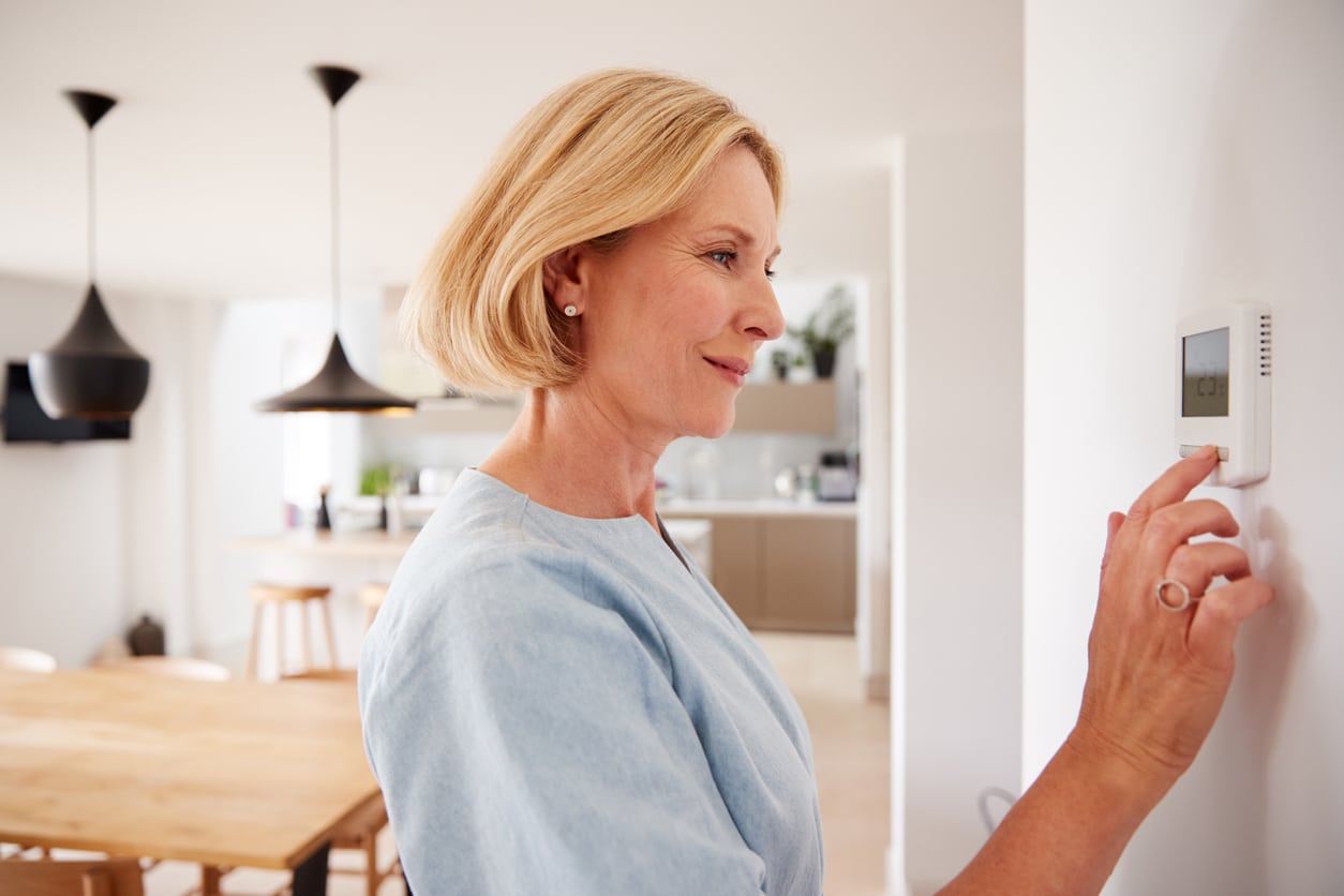 Woman adjusting home thermostat