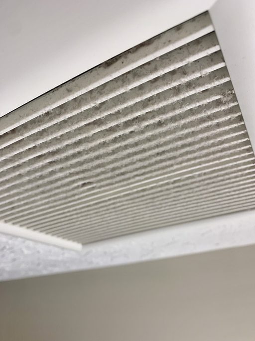 Dirty ceiling air vent with dust buildup