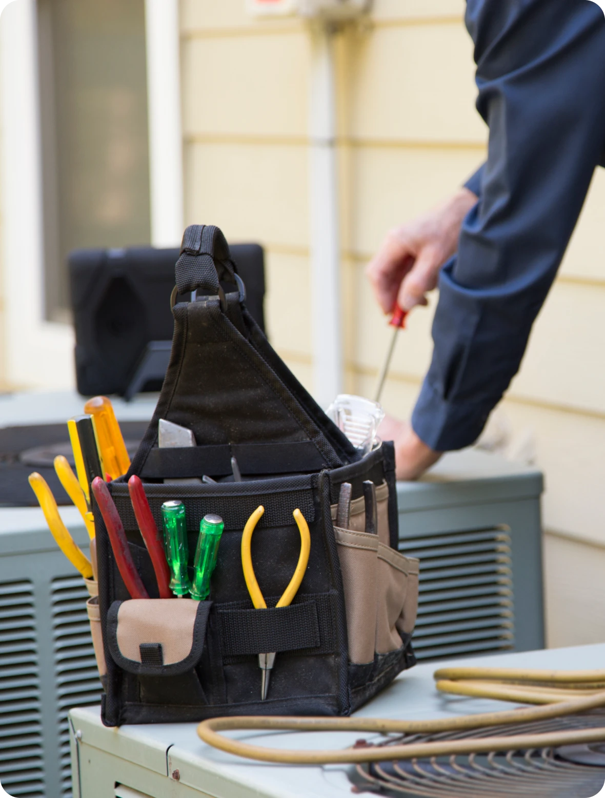 HVAC maintenance with tool bag nearby